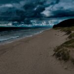 A sandy beach under a dark cloudy sky