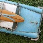 brown surfboard on rusted blue vintage car
