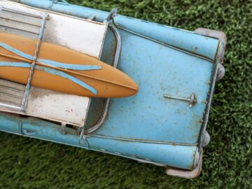 brown surfboard on rusted blue vintage car