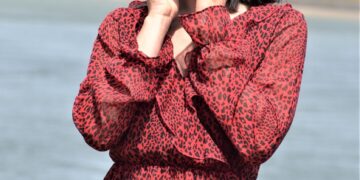 a woman in a red dress holding her hand to her face