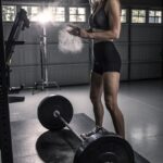 woman in black tank top and black shorts holding barbell