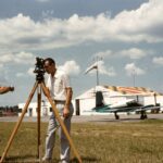 two men standing beside brown wooden tripod