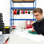 boy in black hoodie writing on white paper