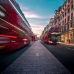 timelapse photography of double decker bus on road between buildings