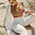 a woman in a bikini top sitting on the beach