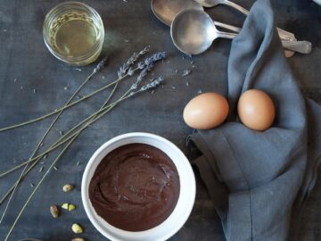 brown egg on white ceramic bowl beside stainless steel spoon