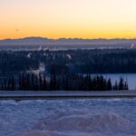 the sun is setting over a snowy landscape