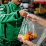 a man handing a bag of fruit to another man