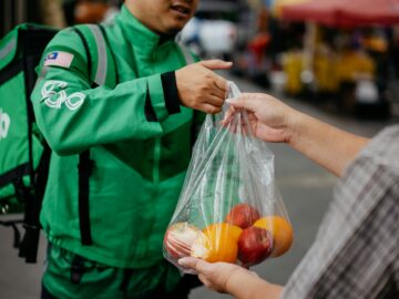 a man handing a bag of fruit to another man