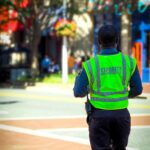 man in green and blue jacket walking on street during daytime