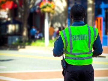 man in green and blue jacket walking on street during daytime