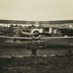 grayscale photography of biplane on field