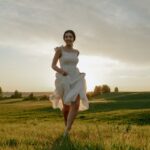 A woman joyfully runs through a sunny meadow, capturing the essence of summer freedom.