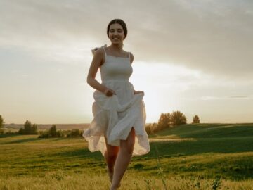 A woman joyfully runs through a sunny meadow, capturing the essence of summer freedom.