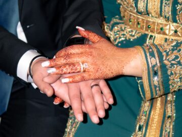 Close-up of hands with intricate henna designs and traditional Moroccan attire, symbolizing love.