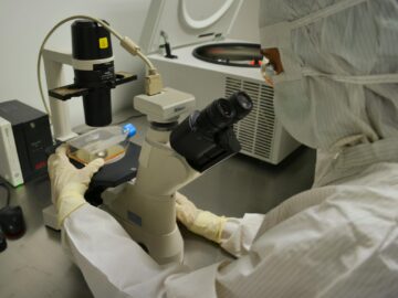 Healthcare professional examining specimen under microscope in laboratory setting.