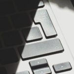 Dramatic light and shadow on a laptop keyboard, emphasizing texture and contrast.