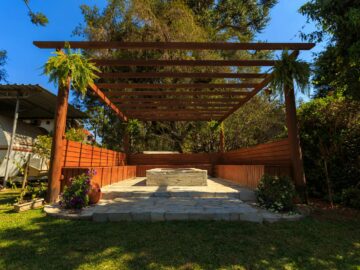 A beautiful wooden gazebo set amidst lush green garden, ideal for outdoor relaxation.