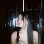 Elegant woman in sequined dress looks to the side in a festive atmosphere.