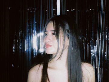 Elegant woman in sequined dress looks to the side in a festive atmosphere.