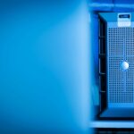 Close-up of a modern server unit in a blue-lit data center environment.