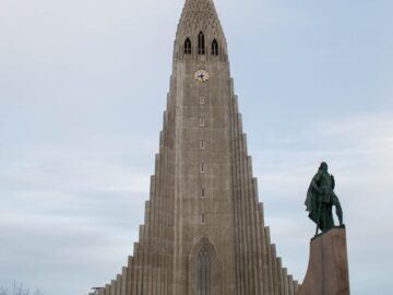 Stunning view of Hallgrímskirkja with statue in Reykjavík, Iceland, showcasing architectural beauty.