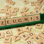 Wooden letter tiles arranged to spell 'Zeugnis' on a green tile holder, creative wordplay concept.