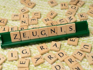 Wooden letter tiles arranged to spell 'Zeugnis' on a green tile holder, creative wordplay concept.