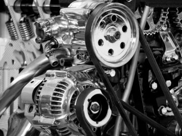 Close-up of a shiny car engine showing polished metal parts and gears in black and white.