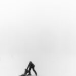 A parent with a child skiing in the misty winter landscape of Crans-Montana, Switzerland.