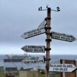 Signpost on Tristan da Cunha indicating distances to various locations, with ocean backdrop.