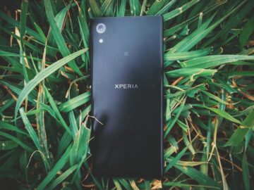 A close-up of a smartphone lying on fresh green grass outdoors.