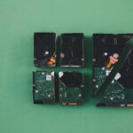 Four broken hard drives arranged on a green background, showcasing data destruction.