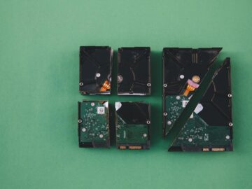 Four broken hard drives arranged on a green background, showcasing data destruction.