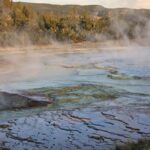 Capture of a steaming geyser field in a geothermal landscape within the United States, showcasing nature's raw power.