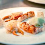 Elegant seafood dish featuring crab claws, lobster, and creative plating, ideal for fine dining contexts.