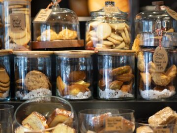 A variety of cookies and pastries artfully displayed in glass jars within a cozy bakery setting.