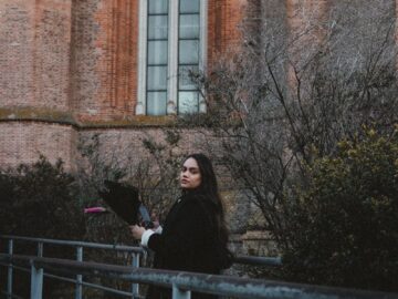 A woman walks by an ancient church facade in La Plata, Argentina, with a view of architectural details.