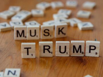 Scrabble game tiles notably spell out 'Musk' and 'Trump' on a wooden table, sparking cultural conversation.