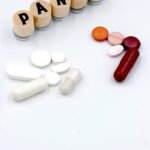 Assorted pills and tablets arranged next to wooden blocks spelling 'PANIC' on a white background.