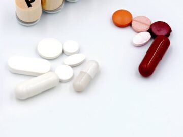Assorted pills and tablets arranged next to wooden blocks spelling 'PANIC' on a white background.