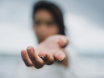 A soft focus image highlighting a reaching hand, symbolizing connection or help.