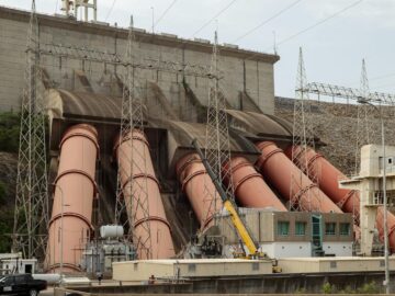 Complex view of a hydroelectric dam with large turbines and power lines demonstrating energy infrastructure.