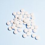 A collection of white tablets scattered on a light blue surface, perfect for health-related content.