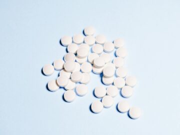 A collection of white tablets scattered on a light blue surface, perfect for health-related content.