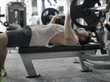 A man performing an intense bench press workout in a modern gym, showcasing strength and focus.