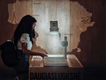 A young woman interacts with an overhead projector in a dimly lit educational setting.