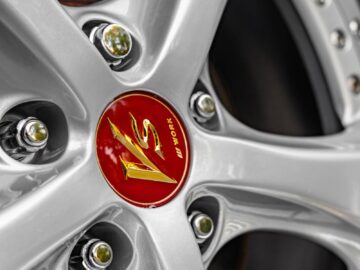 Closeup of clean modern stainless steel wheel rim in form of beams with shiny surface and colorful center part surrounded by symmetrical nuts with bolts