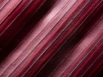 Close-up of maroon fabric with a textured striped pattern, ideal for textile design backgrounds.