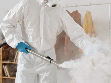 A professional in PPE disinfects an indoor space, emphasizing safety and hygiene.